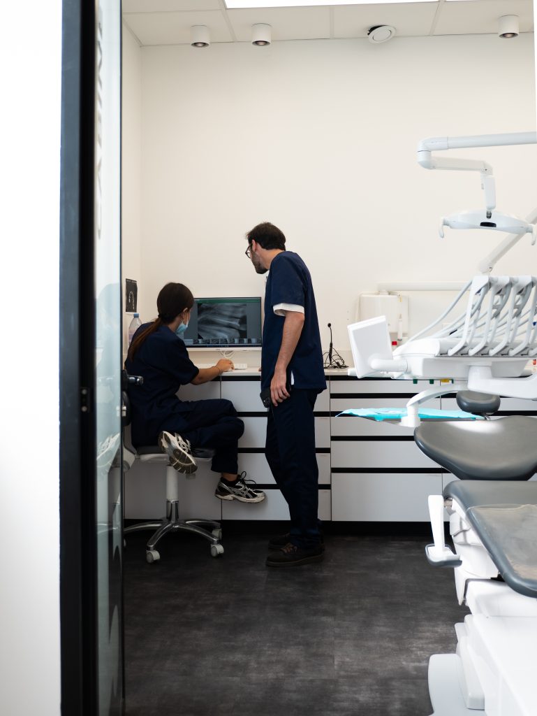 Vue d'ensemble d'une salle de soins dentaires moderne avec fauteuil professionnel et espace de diagnostic.
