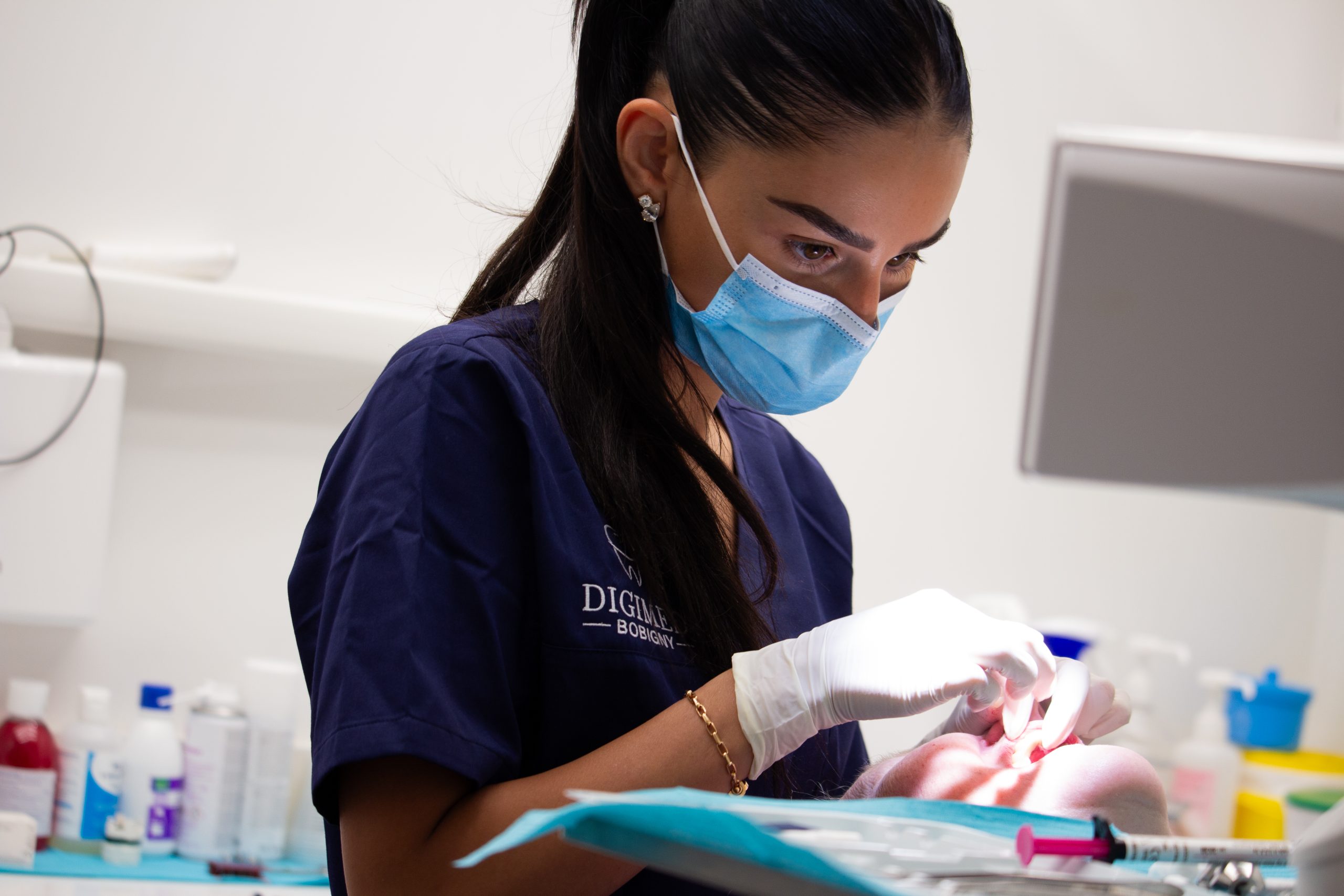 Une femme chirurgien-dentiste concentrée lors d'une consultation et de soins dentaires au sein du cabinet.