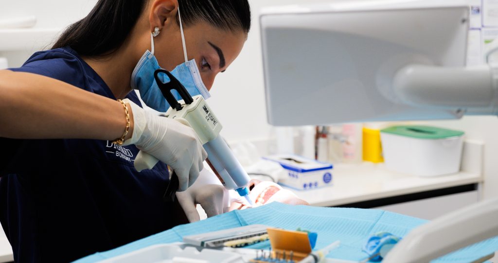 Utilisation d'un pistolet mélangeur pour préparer la colle orthodontique avant la pose des attaches.